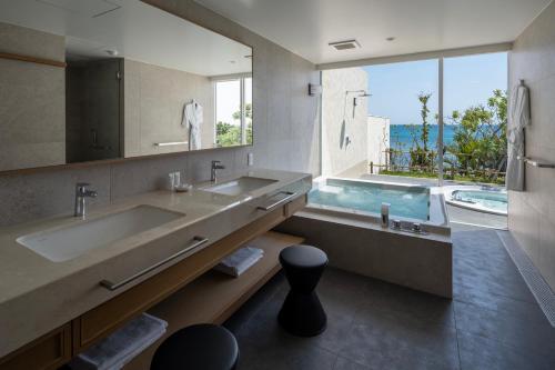 a bathroom with a large sink and a large mirror at アルカディアリゾート宮古島 in Irabu