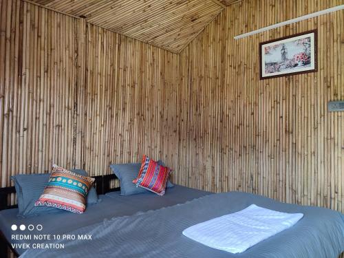 1 dormitorio con 1 cama en una pared de madera en The Jungle Mist Resort, en Rishīkesh