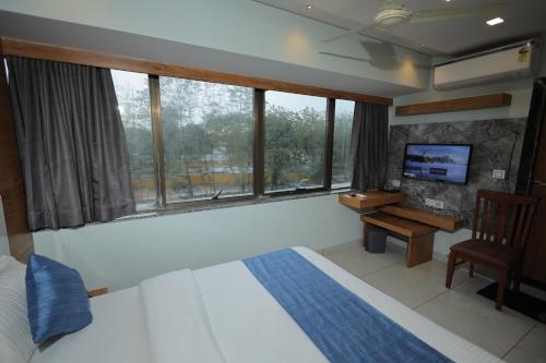 a bedroom with a bed and a desk and windows at HOTEL RK FORTUNE in Ahmedabad