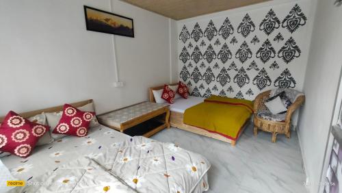 - une petite chambre avec 2 lits et une chaise dans l'établissement Holidays homestay, à Mirik