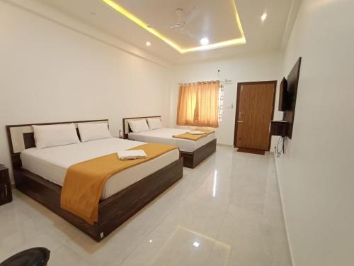 Habitación de hotel con 2 camas y TV en Kurinji Inn en Attigundi