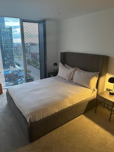 a bed in a room with a large window at Lux 2 Bedroom MCR Deansgate in Manchester