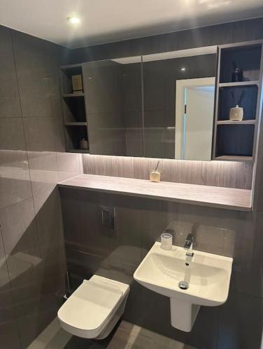 a bathroom with a sink and a toilet and a mirror at Lux 2 Bedroom MCR Deansgate in Manchester