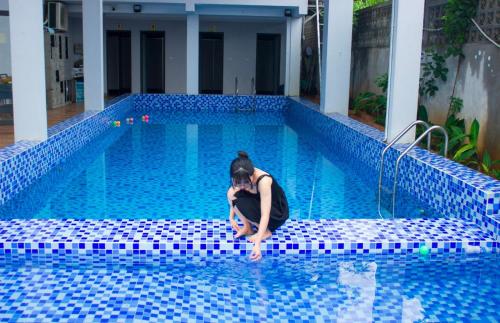 una mujer sentada en el borde de una piscina en Nature Key Retreat Gia Trịnh - Ba Vì, en Hanói