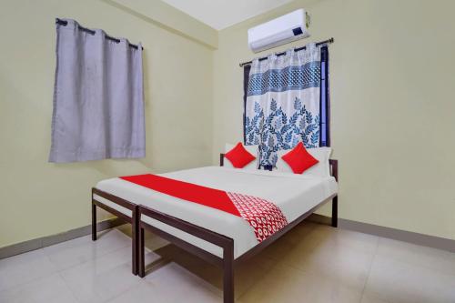 Un dormitorio con una cama con almohadas rojas y una ventana en OYO Ruby Grand Inn Nallagandla, en Lingampalli