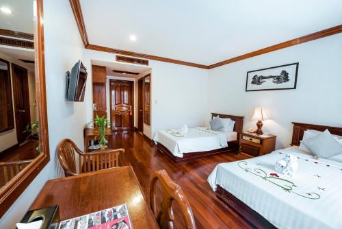 a hotel room with two beds and a table at Royal Crown Hotel & Spa in Siem Reap