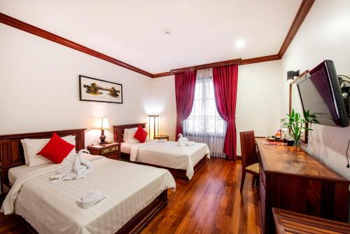 a hotel room with two beds and a flat screen tv at Royal Crown Hotel & Spa in Siem Reap