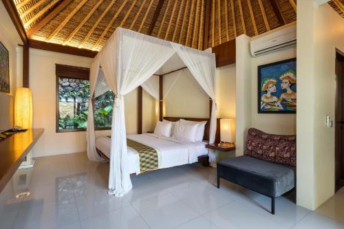 1 dormitorio con cama con dosel y silla en Ubud Green Resort Villas Powered by Archipelago, en Ubud