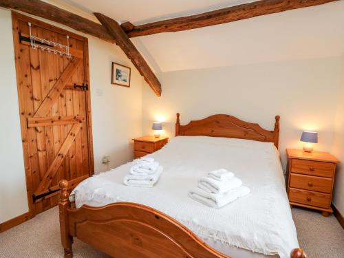 a bedroom with a wooden bed with towels on it at Llety'r Wennol in Llanycrwys