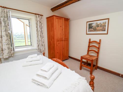 a bedroom with a bed and a chair and a window at Llety'r Wennol in Llanycrwys