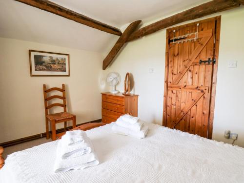 a bedroom with a white bed and a wooden door at Llety'r Wennol in Llanycrwys
