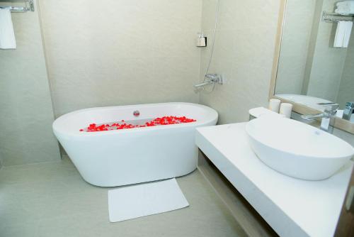 a white bathroom with a tub and a sink at Hera Luxury Hotel in Ho Chi Minh City