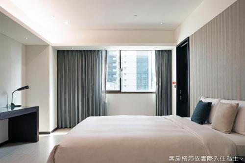 Un dormitorio con una cama grande y una ventana en Talmud Hotel Kaohsiung LoveRiver, en Kaohsiung