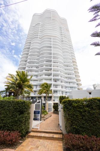 a large white building with palm trees in front of it at Burleigh Surf Apartments in Gold Coast