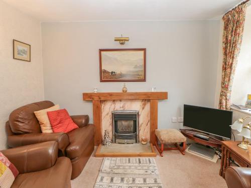 a living room with a couch and a fireplace at Blacksmith Cottage in Appleby