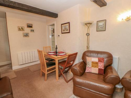 a living room with a table and a leather chair at Blacksmith Cottage in Appleby