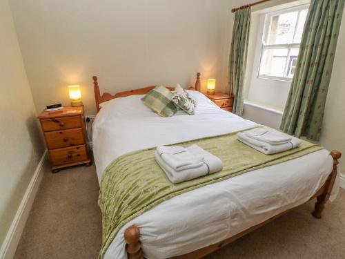 a bedroom with a bed with two towels on it at Blacksmith Cottage in Appleby