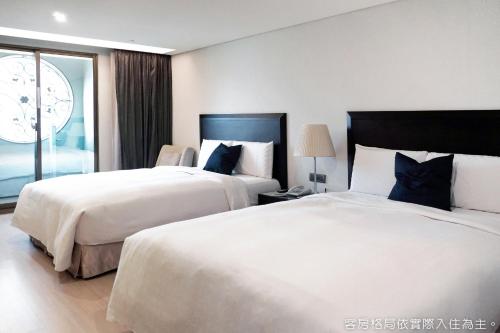 a hotel room with two beds and a window at Talmud Hotel Kaohsiung LoveRiver in Kaohsiung