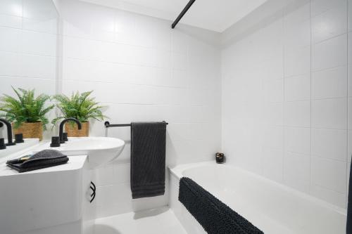 y baño blanco con lavabo y bañera. en Welcome Homestay Gurambai, en Darwin