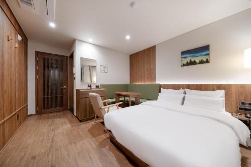 a bedroom with a large white bed and a desk at Simjak Hotel Dongtan By Aank in Hwaseong
