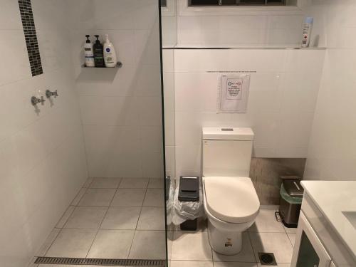a white bathroom with a toilet and a sink at Central Oasis in Coffs Harbour