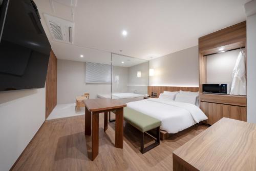a bedroom with a bed and a table and a television at Simjak Hotel Dongtan By Aank in Hwaseong
