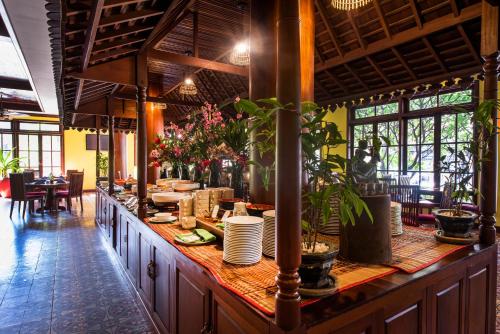 a restaurant with a long counter with plates and plants at Royal Crown Hotel & Spa in Siem Reap