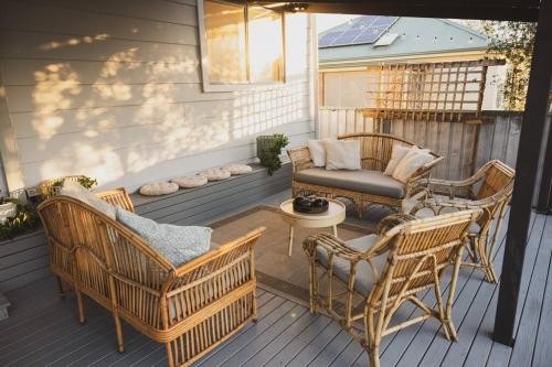een patio met rieten stoelen en een bank op een veranda bij Halcyon Days the perfect getaway, pet friendly! in Cessnock
