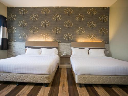 two beds in a hotel room with a wall at Sky Star Hotel KLIA/KLIA2 in Sepang