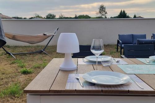 una mesa de madera con un plato y una copa de vino. en Belle maison 3 chambres - Jusqu'à 9 personnes - Ideal entre Collègues ou Famille -La Bohème -, en Saint-Seurin-sur-lʼIsle