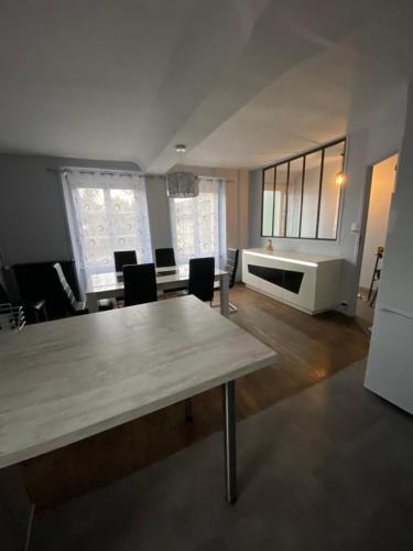 salon ze stołem, krzesłami i oknami w obiekcie Maison centre ville w mieście Vire