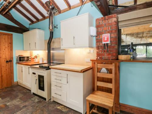 a kitchen with white cabinets and a brick wall at The Barn in Chippenham