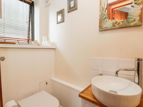 Baño blanco con lavabo y espejo en The Barn en Chippenham