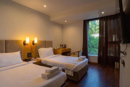 a hotel room with two beds and a window at Emerald Hotel in Āīzawl