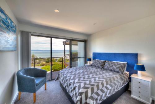a bedroom with a bed and a chair and a window at Tranquility in Coles Bay