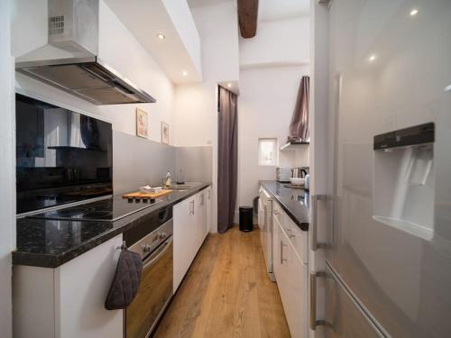 une grande cuisine avec des armoires blanches et des comptoirs noirs dans l'établissement Appartement tout équipé 4 couchages avec terrasse et Parking, à Venelles