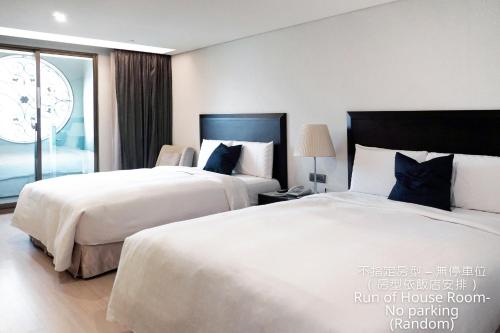 a hotel room with two beds and a window at Talmud Hotel Kaohsiung LoveRiver in Kaohsiung