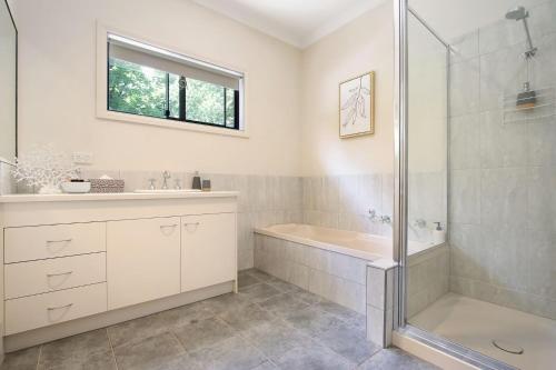 a bathroom with a shower and a tub and a sink at Brookside in Bright