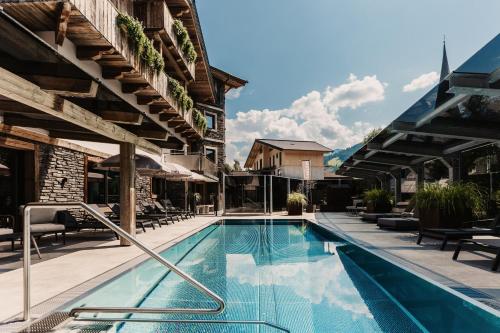 uma piscina num hotel com mesas e cadeiras em Knappensteig Appartements em Wagrain