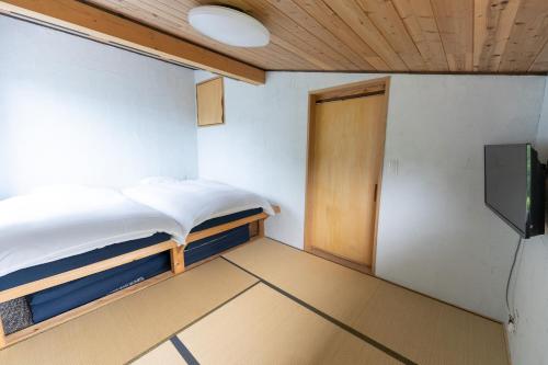 a room with a bed and a door and a television at Niseko Nikuyadoya in Niseko