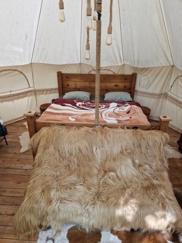 a bed in a tent with a furry rug on the floor at Glamping Stola- Šepot kvetov in Štôla