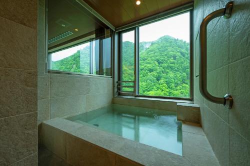 Grand Blissen Hotel Jozankei في Jozankei: حمام مع حوض استحمام مع نافذة