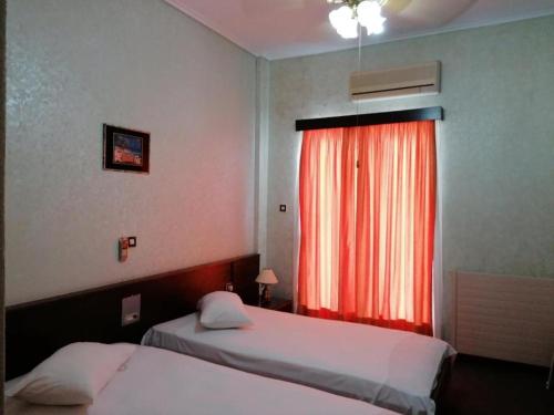 a bedroom with two beds and a red window at HOTEL ALEXANDROS in Loutraki