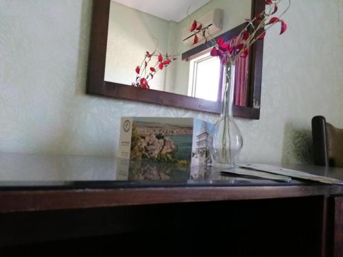 a table with a vase of flowers and a mirror at HOTEL ALEXANDROS in Loutraki