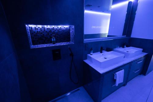 a blue bathroom with two sinks and a mirror at High Class Suites Mazuria in Mrągowo