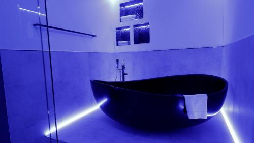 a black bath tub in a bathroom with lights at High Class Suites Mazuria in Mrągowo