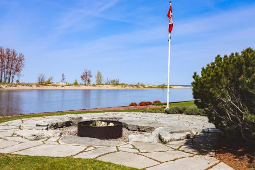 a flag pole and a fire pit next to a lake at The Gardenhouse Cottage One in Wasaga Beach
