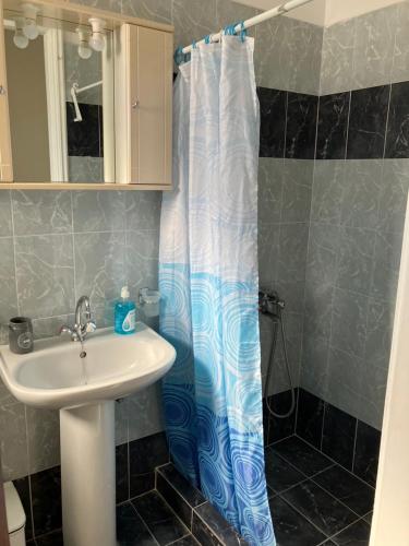 a bathroom with a sink and a shower curtain at VOULA'S HOUSES in Karlovasi