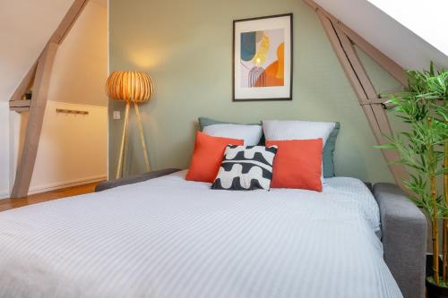 1 dormitorio con cama y almohadas de color naranja en Le Cocon Forestier - Proche aéroport Beauvais, Chantilly, forêt de Hez-Froidmont, parking public gratuit, Wifi & Netflix, en Clermont