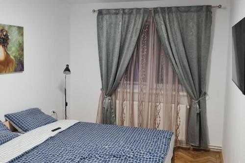 1 dormitorio con 1 cama y una ventana con cortinas en Apartament 3 camere, doua bai integral pentru familie sau grup, en Cugir